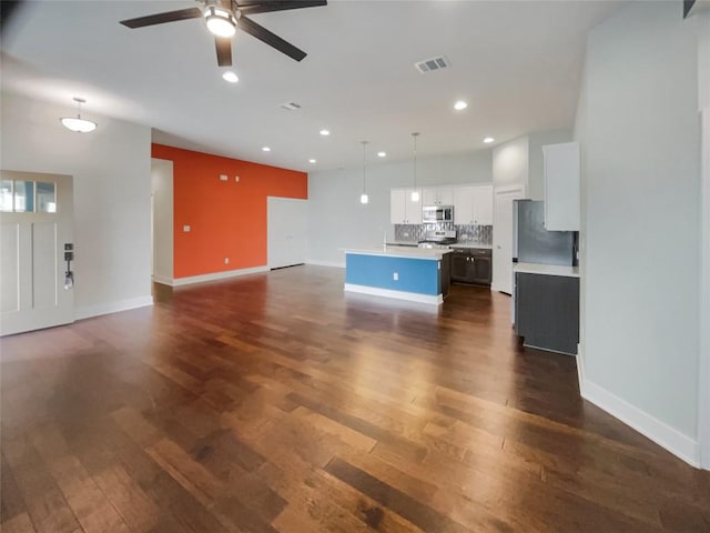 unfurnished living room with baseboards, visible vents, dark wood finished floors, a ceiling fan, and recessed lighting