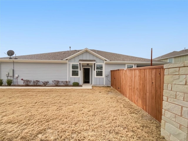 view of front of house featuring fence, board and batten siding, and roof with shingles