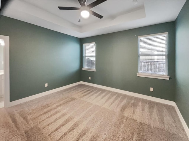 unfurnished room with carpet, a raised ceiling, ceiling fan, and baseboards