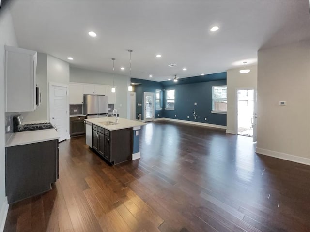 kitchen with dark wood finished floors, light countertops, stove, freestanding refrigerator, and a sink