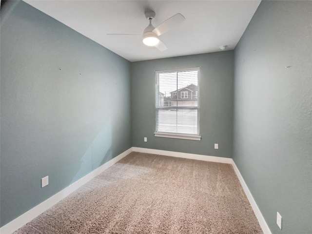 carpeted empty room with ceiling fan and baseboards