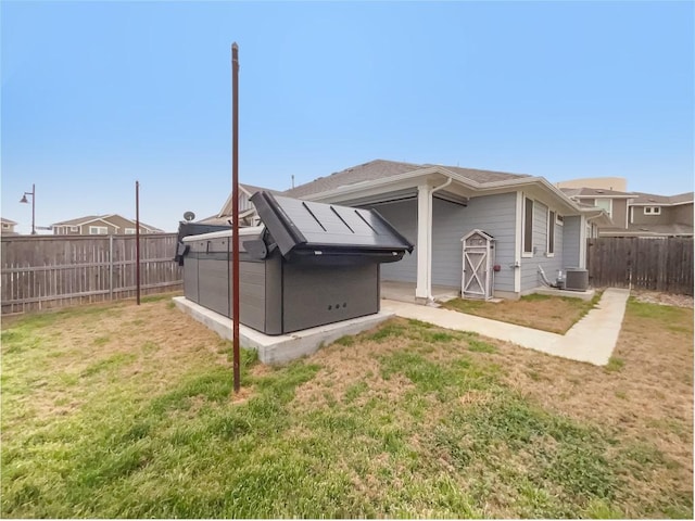 rear view of house featuring a fenced backyard, a yard, and central air condition unit