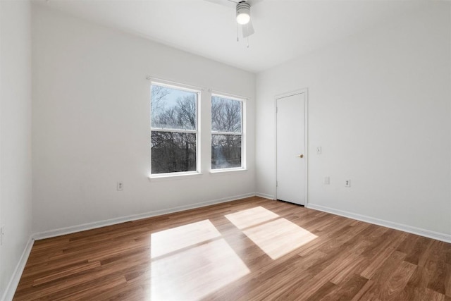 spare room featuring ceiling fan, baseboards, and wood finished floors