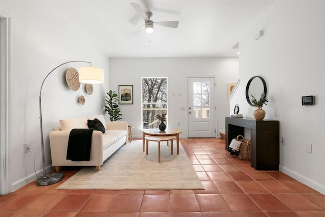 living area with ceiling fan, baseboards, and tile patterned floors