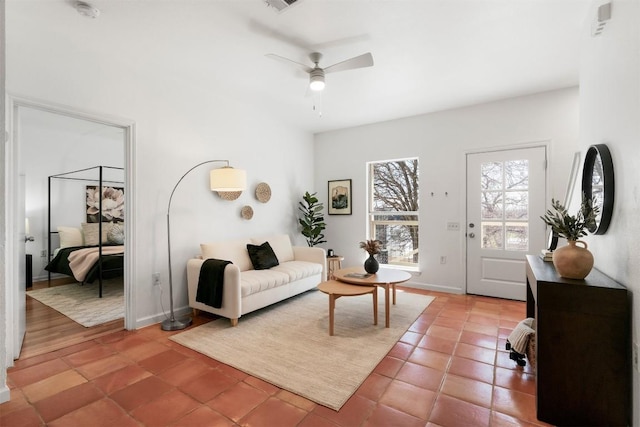 living area with a ceiling fan, baseboards, and light tile patterned floors