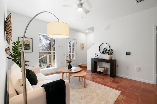 tiled living room with visible vents, baseboards, and a ceiling fan