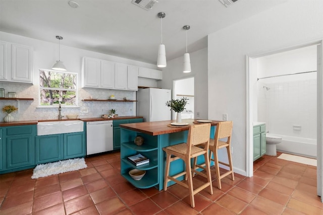 kitchen with white appliances, wood counters, open shelves, and a sink