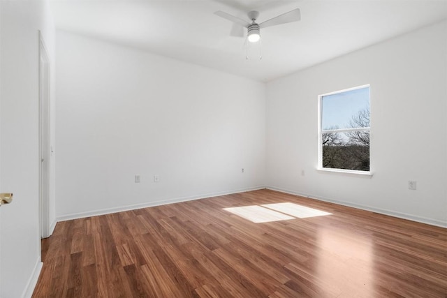 unfurnished room with wood finished floors, a ceiling fan, and baseboards