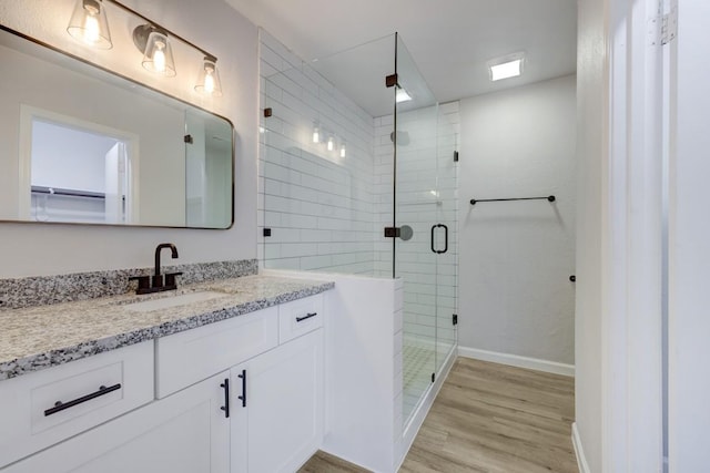 full bath featuring a shower stall, baseboards, wood finished floors, and vanity