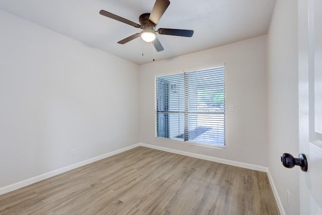 spare room featuring light wood finished floors, baseboards, and a ceiling fan