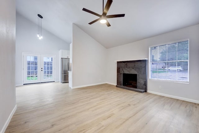 unfurnished living room featuring a healthy amount of sunlight, light wood finished floors, a fireplace, and french doors