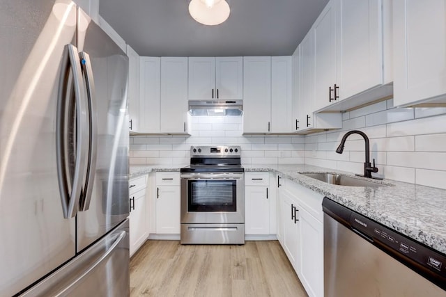 kitchen featuring under cabinet range hood, stainless steel appliances, a sink, white cabinets, and light wood-type flooring