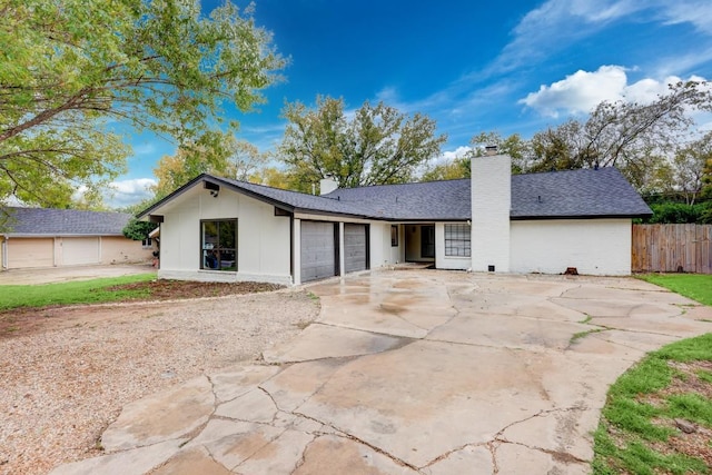 single story home with a garage, driveway, a shingled roof, a chimney, and fence