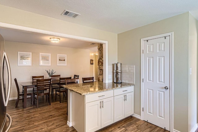 kitchen with dark wood finished floors, tasteful backsplash, visible vents, white cabinets, and light stone countertops