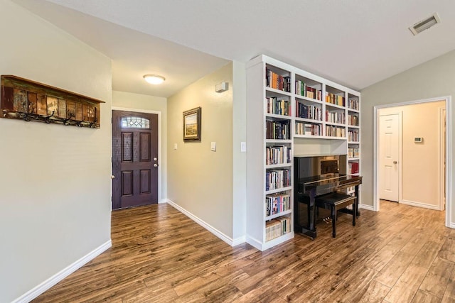 entryway featuring baseboards, visible vents, vaulted ceiling, and wood finished floors