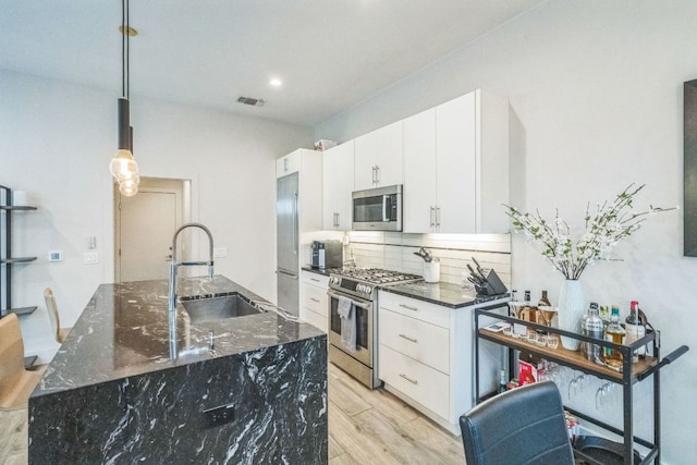 kitchen featuring tasteful backsplash, visible vents, stainless steel appliances, light wood-type flooring, and a sink