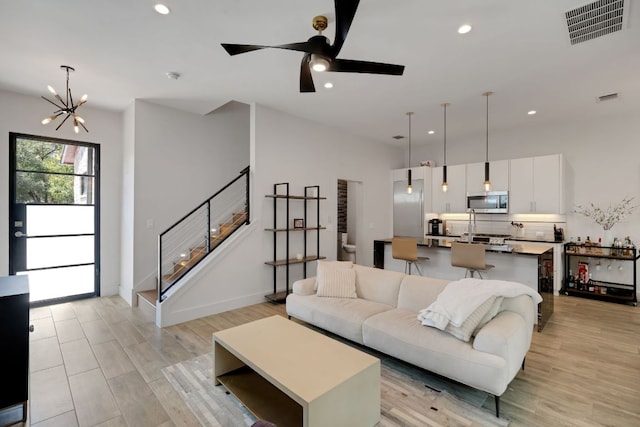 living room with stairs, light wood-type flooring, visible vents, and recessed lighting