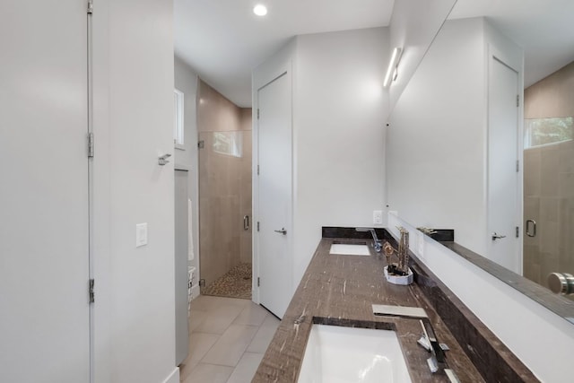 bathroom with double vanity, a stall shower, tile patterned flooring, and a sink