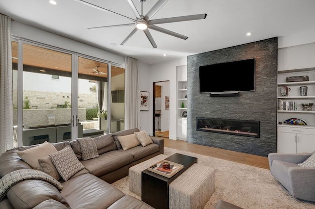 living room with built in features, ceiling fan, wood finished floors, a fireplace, and recessed lighting