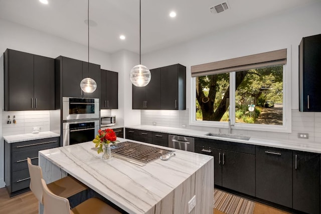 kitchen with stainless steel appliances, dark cabinetry, a kitchen island, and visible vents