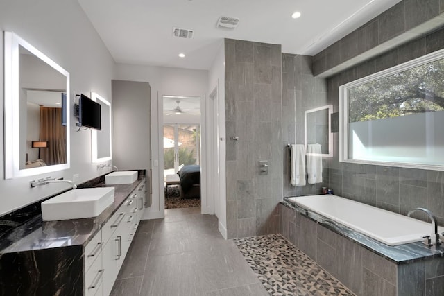 ensuite bathroom with double vanity, tiled bath, visible vents, ensuite bathroom, and a sink