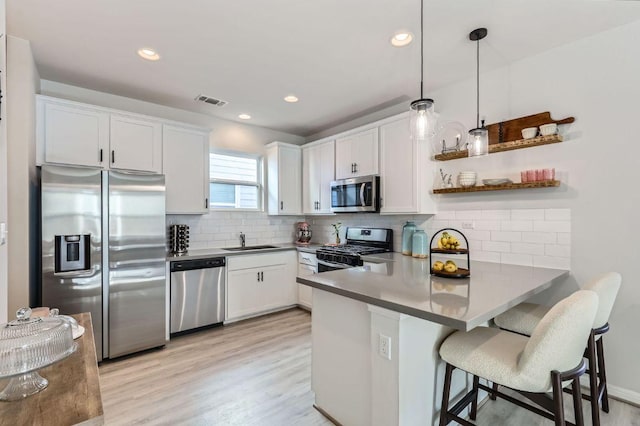 kitchen with visible vents, a peninsula, a sink, appliances with stainless steel finishes, and white cabinetry