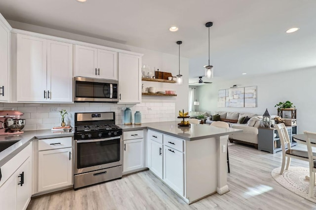 kitchen featuring a peninsula, white cabinets, backsplash, and stainless steel appliances