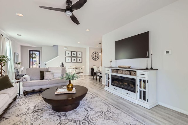 living area featuring a ceiling fan, wood finished floors, baseboards, recessed lighting, and a fireplace