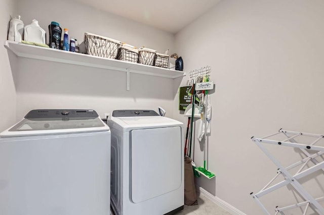 washroom with laundry area, separate washer and dryer, and baseboards