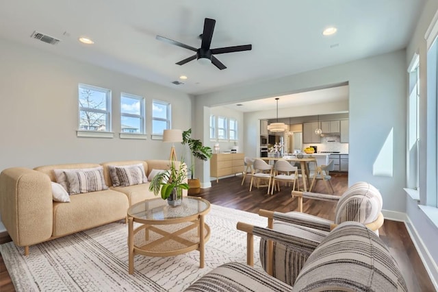 living room featuring baseboards, dark wood-style flooring, visible vents, and recessed lighting