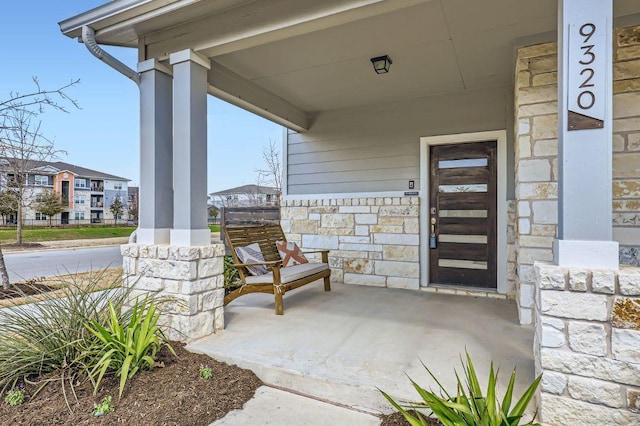 doorway to property with stone siding and covered porch