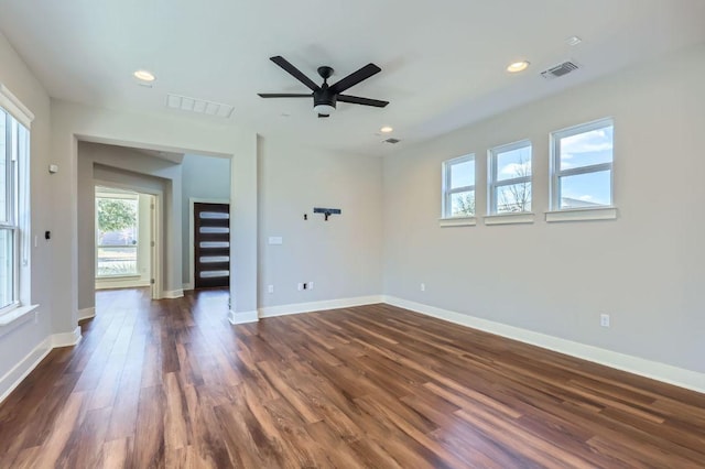 unfurnished room featuring dark wood-type flooring, visible vents, and baseboards