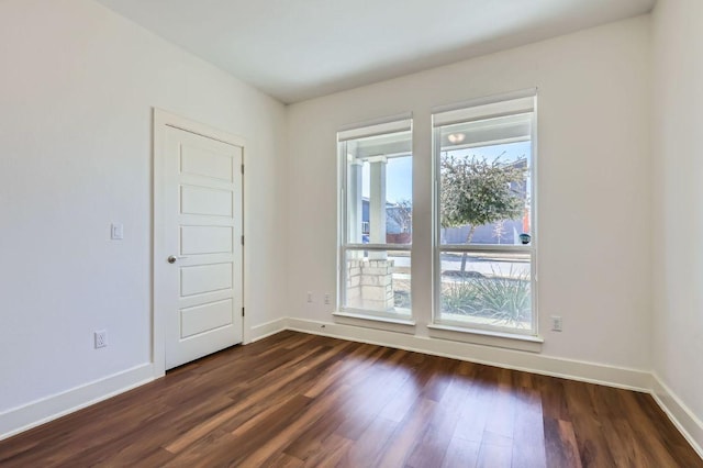 unfurnished room featuring dark wood-style flooring and baseboards