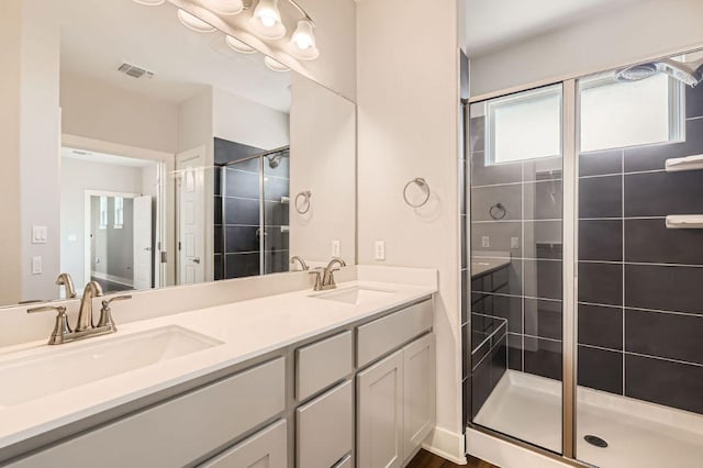 bathroom featuring a stall shower, visible vents, a sink, and double vanity