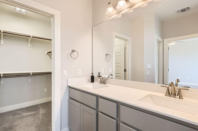 full bath featuring double vanity, a sink, visible vents, and baseboards