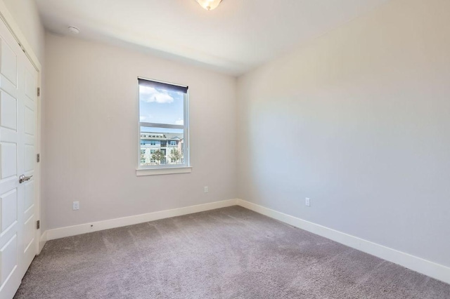 carpeted spare room featuring baseboards