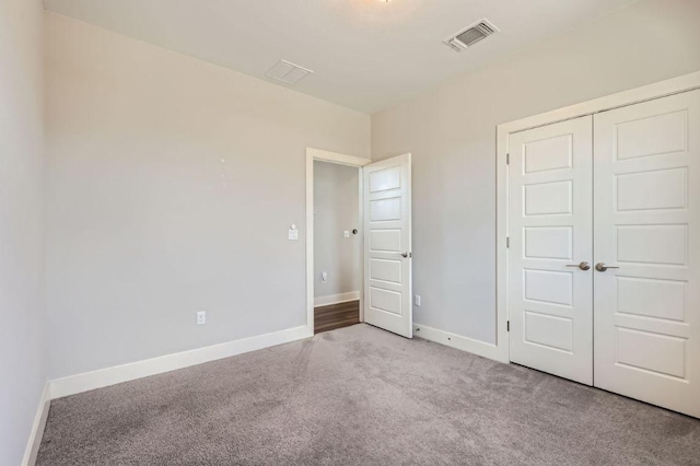 unfurnished bedroom featuring carpet, a closet, visible vents, and baseboards