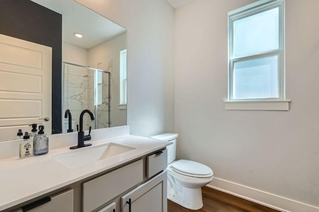 bathroom featuring a stall shower, baseboards, toilet, wood finished floors, and vanity