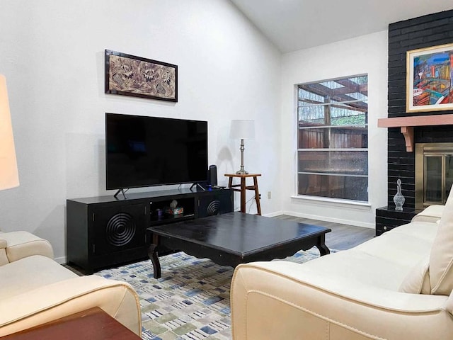 living room featuring lofted ceiling, a fireplace, wood finished floors, and baseboards