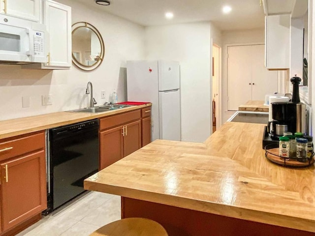 kitchen with light tile patterned floors, recessed lighting, butcher block counters, white appliances, and a sink