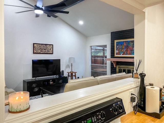 living area with a ceiling fan, lofted ceiling, a brick fireplace, and wood finished floors