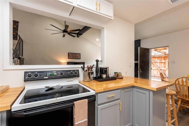 7215 Coronado Cir, Austin, TX 78752 - kitchen with range with electric cooktop, butcher block countertops, ceiling fan, gray cabinetry, and vaulted ceiling