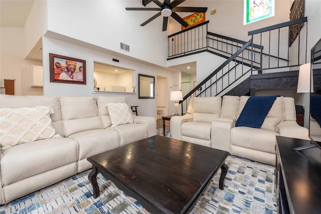 living room featuring stairway, a high ceiling, visible vents, and a ceiling fan