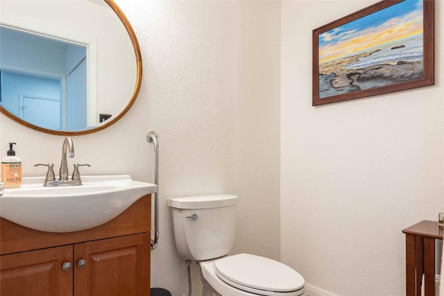 bathroom featuring toilet, baseboards, and vanity