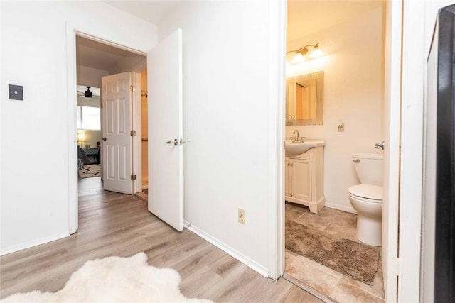 half bathroom with wood finished floors, vanity, toilet, and baseboards