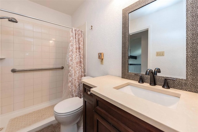 full bathroom with toilet, a textured wall, a tile shower, and vanity