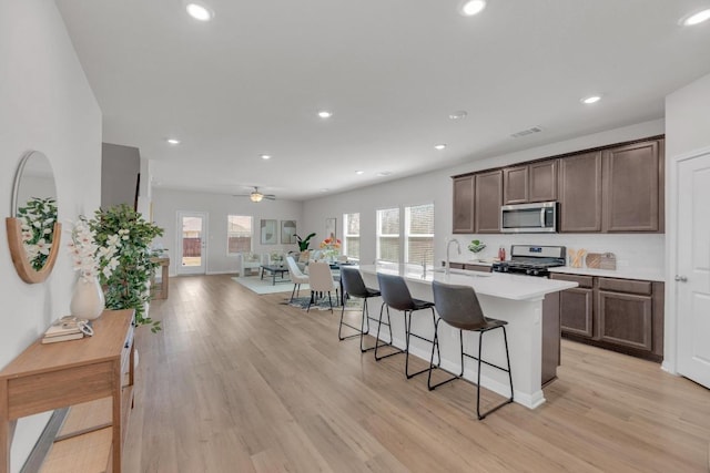 kitchen featuring a breakfast bar area, a sink, appliances with stainless steel finishes, light wood-type flooring, and plenty of natural light