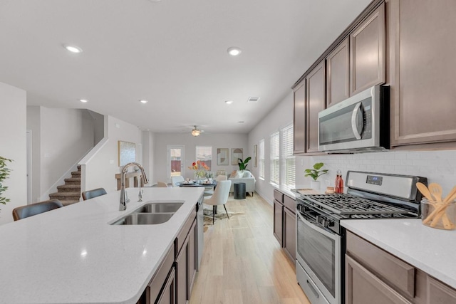 kitchen featuring light wood finished floors, recessed lighting, decorative backsplash, appliances with stainless steel finishes, and a sink