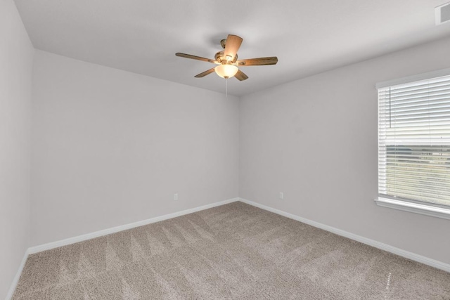 carpeted empty room featuring visible vents, a ceiling fan, and baseboards