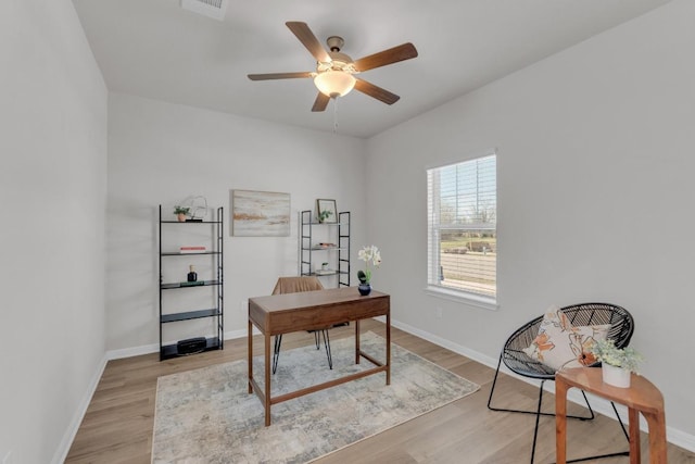 home office featuring light wood finished floors, visible vents, baseboards, and a ceiling fan